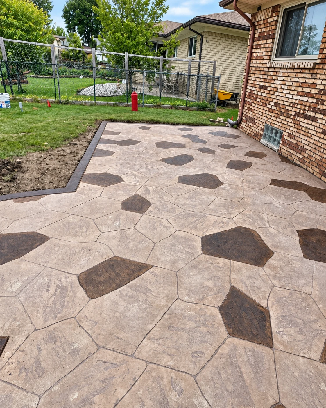 A finished two-tone stamped concrete patio with dark accent stones and a charcoal border